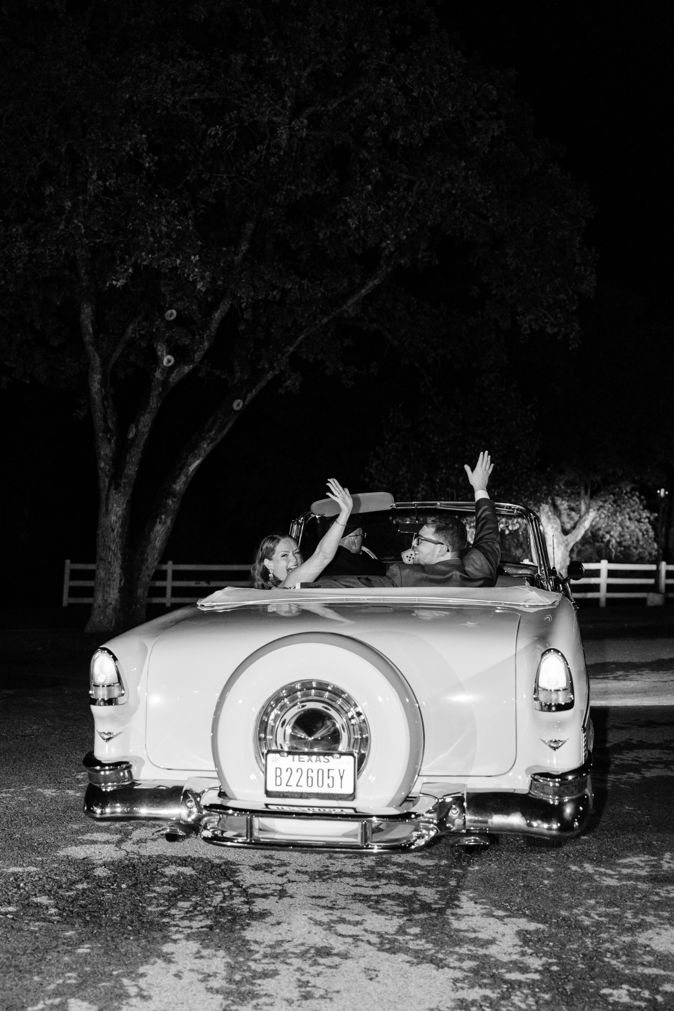 Newlywed couple smiling from the back seat of Ole' Belle