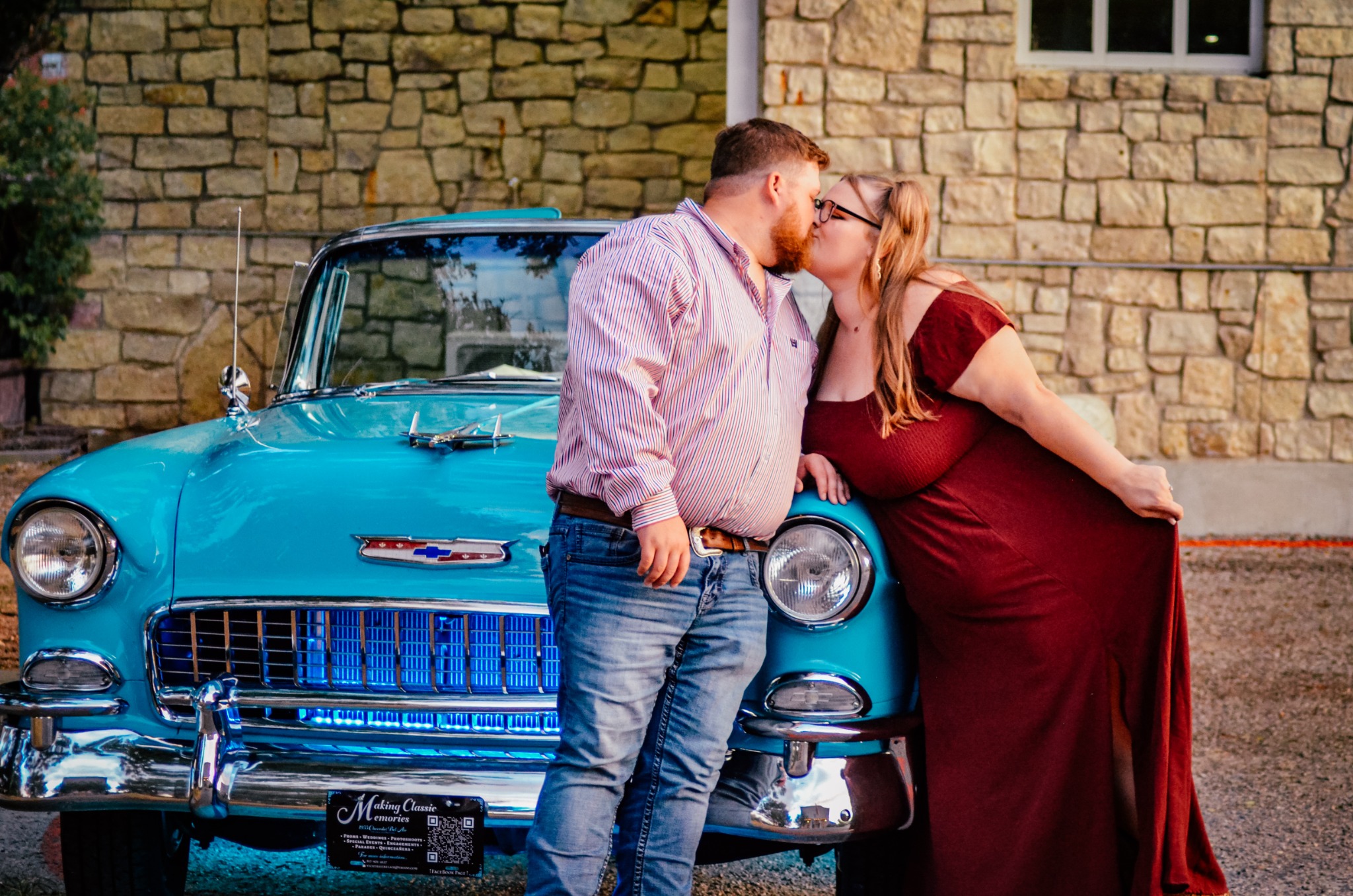 Engaged couple sharing a kiss beside turquoise-and-white Ole' Belle