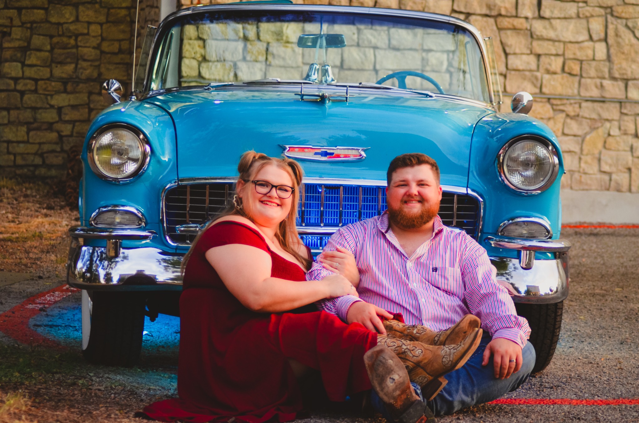 Engaged couple seated together in front of the 1955 Chevrolet Bel Air