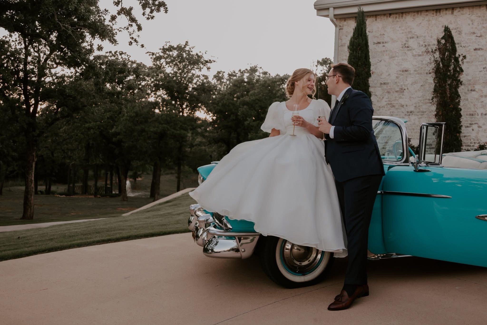 Newlywed couple celebrating beside Ole' Belle, a turquoise and white 1955 Chevrolet Bel Air Convertible