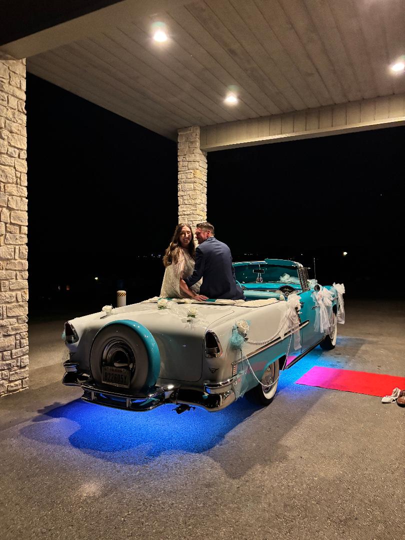 Newlyweds seated in Ole' Belle as the decorated car waits beneath the venue entrance