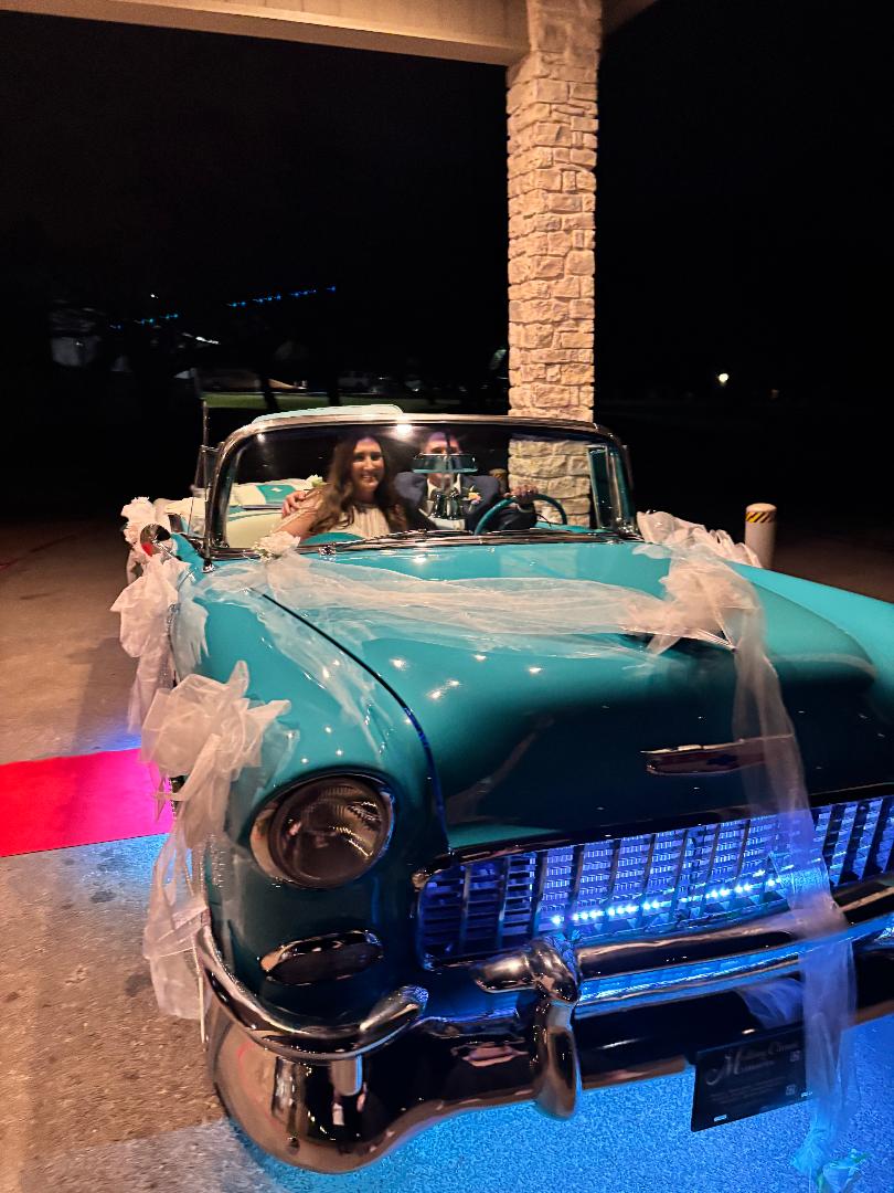 Newlyweds seated in Ole' Belle above the red carpet and blue LED lights