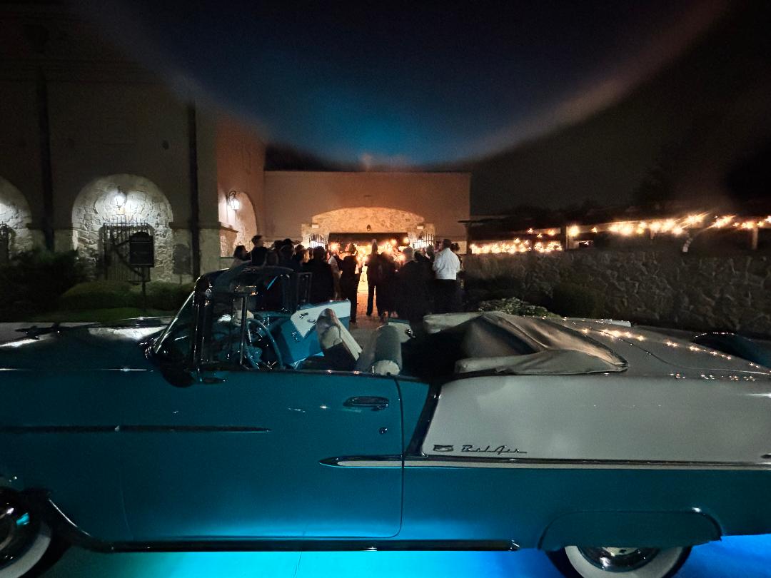Ole' Belle glowing turquoise at night as guests gather near the venue
