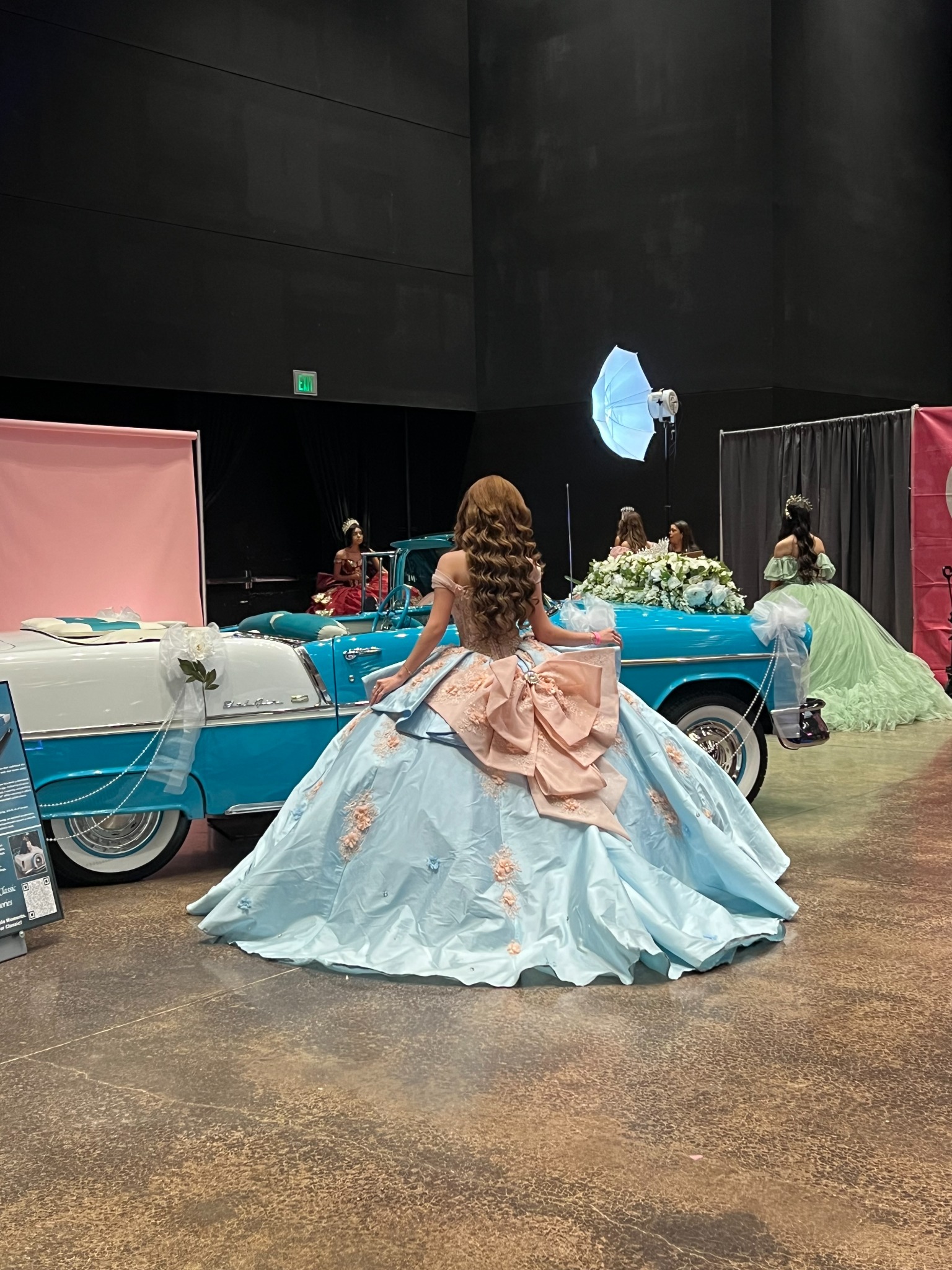 Back view of an elegant quinceañera dress beside Ole' Belle at an expo