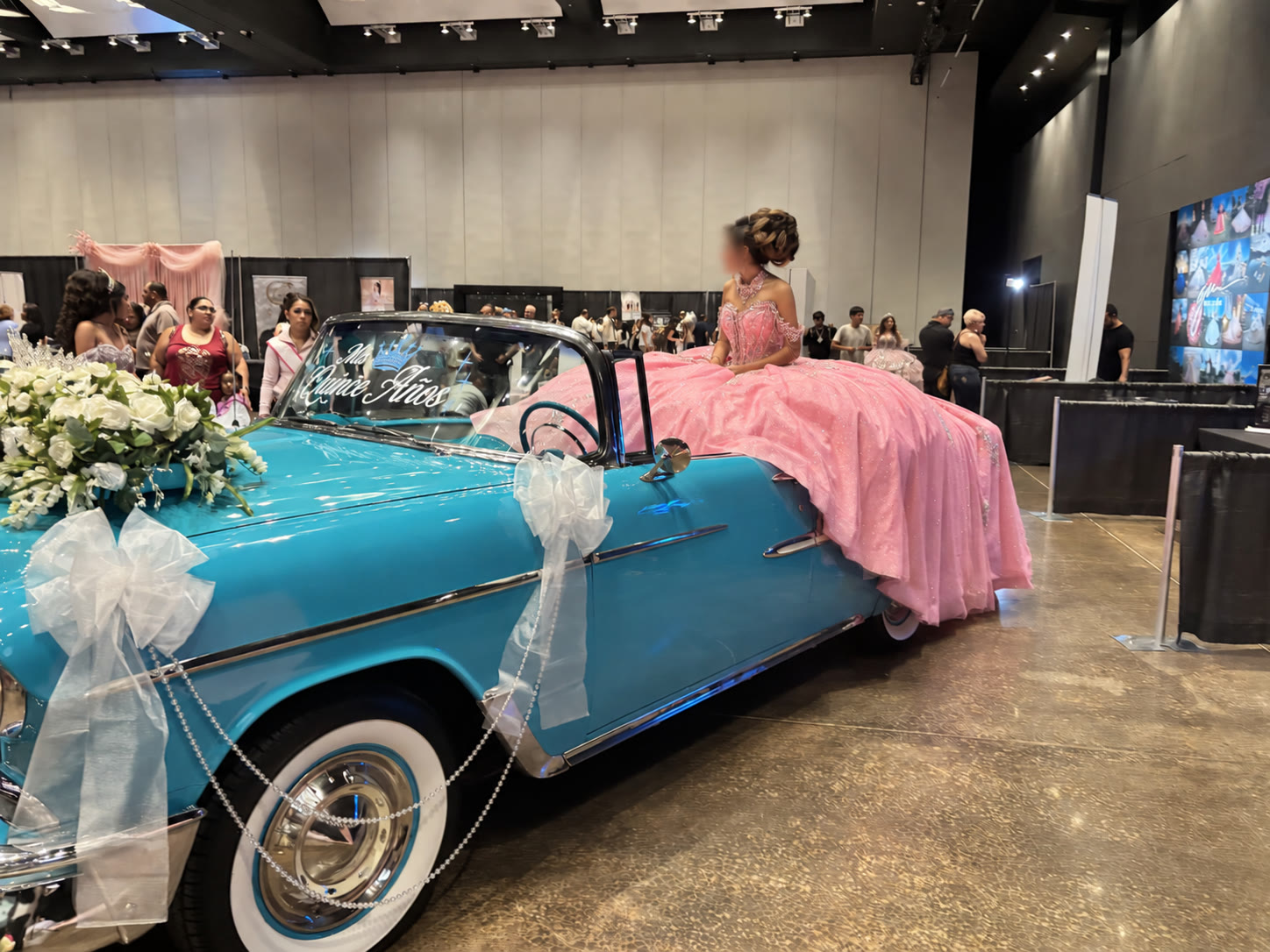 Ole' Belle decorated with white flowers beside a pink quinceañera gown at an expo